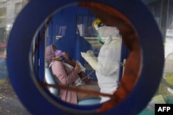 Seorang nakes melakukan pemeriksaan kesehatan sebelum menjalani tes PCR COVID-19 di sebuah sekolah di Bandung, Jawa Barat, 7 Februari 2022. (Timur Matahari/AFP)