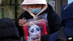 Seorang pria memegang boneka maskot Olimpiade Musim Dingin Beijing Bing Dwen Dwen yang ia beli dari salah satu toko di Beijing, pada 7 Februari 2022. (Foto: AP/Andy Wong)