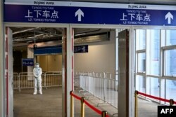 FILE - A man stands guard an exit within the closed-loop "bubble" at the Taizicheng train station, in Zhangjakou on Jan. 29, 2022, ahead of the 2022 Beijing Winter Olympic Games.