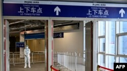 Seorang pria berjaga di pintu keluar stasiun kereta Taizicheng, di Zhangjakou pada 29 Januari 2022. Beijing, Rabu (4/5), menutup sekitar 10% stasiun di sistem kereta bawah tanahnya yang luas sebagai tindakan tambahan terhadap penyebaran virus corona.(Foto: AFP)