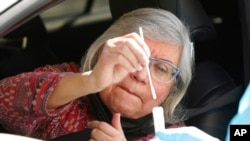 Diana Merchant self-tests for COVID-19 at a drive-thru testing site in Whittier, Calif., Jan. 25, 2022.