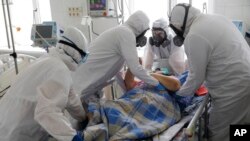Medical staff members wearing special suits to protect against coronavirus treat a patient with coronavirus at an ICU of the Clinical hospital in Volgograd, Russia, Jan. 31, 2022. 