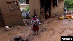 A girl holds a baby outside a damaged house in a flooded area, as Cyclone Batsirai sweeps inland, in Fianarantsoa, Madagascar, Feb. 6, 2022.