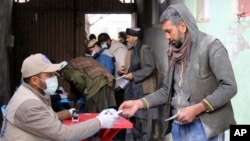 FILE - Afghans wait to receive food rations organized by the World Food Program in Pul-e-Alam, the capital of Logar province in eastern Afghanistan, Jan. 18, 2022. 
