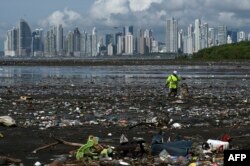In this file photo taken on April 19, 2021 a man collects garbage, including plastic waste, at the beach of Costa del Este, in Panama City. (Photo by Luis ACOSTA / AFP)