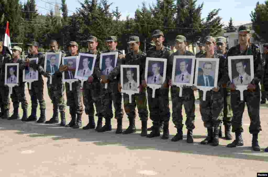 Forces loyal to Syria&#39;s President Bashar al-Assad carry pictures of him and his late father, former Syrian president Hafez al-Assad, as they commemorate the 67th anniversary of the founding of the Baath party, at an undisclosed location, April 7, 2014.