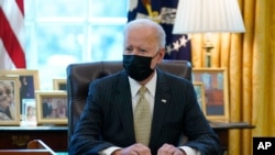 FILE - President Joe Biden is seen sitting at his desk in the Oval Office of the White House in Washington, March 30, 2021. 