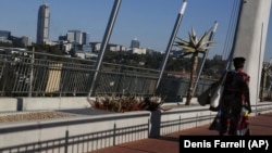 A woman walks toward the Johannesburg suburb of Sandton (background) on a bridge that connects it to the black township of Alexandra. 