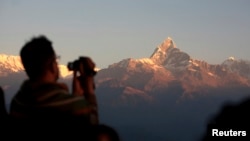 FILE - Tourists take pictures at Sarangkot in Pokhara, with the view of the Mount Annapurna range in the background, some 200 km (124 miles) west of Kathmandu, Nov. 30, 2008. Annapurna, at 8,091 meters high, is the 10th highest mountain in the world. 