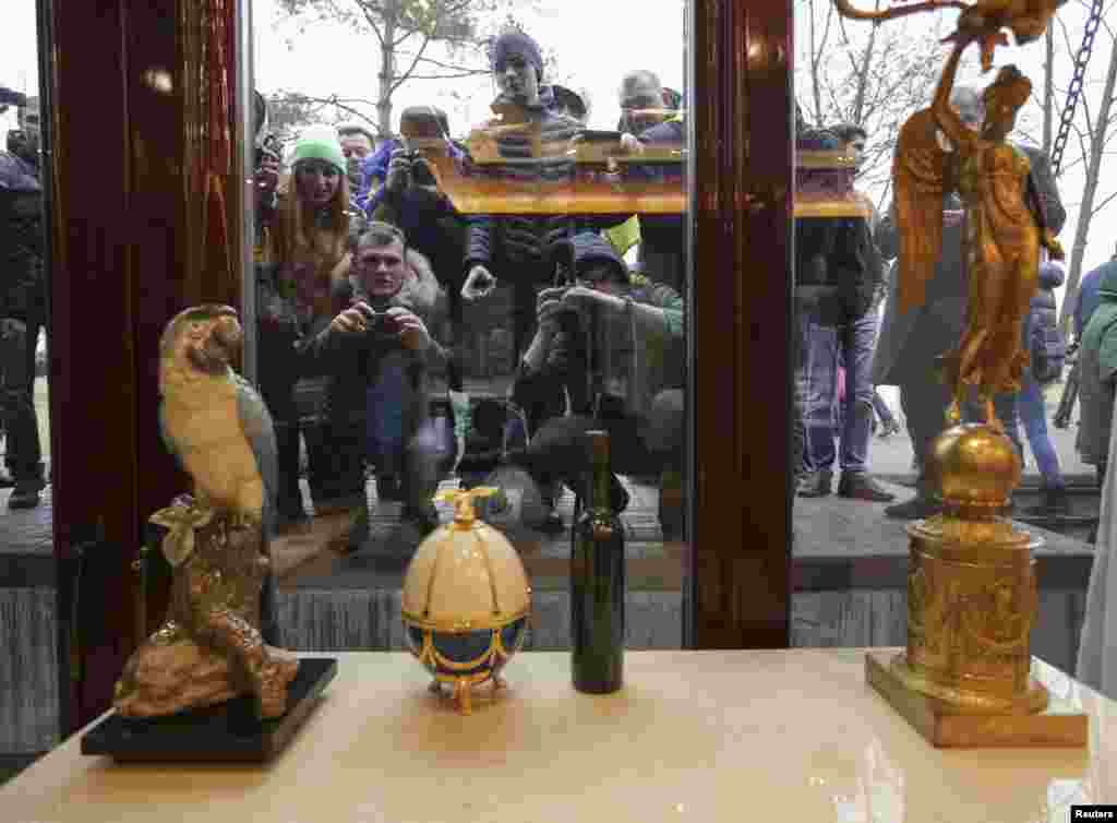 People look through windows of the Mezhyhirya residence of Viktor Yanukovych as anti-government protesters and journalists walk on the grounds in the village Novi Petrivtsi, Feb. 22, 2014.