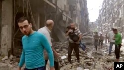 Warga di antara puing-puing bangunan yang rusak karena serangan udara di Aleppo (28/4).