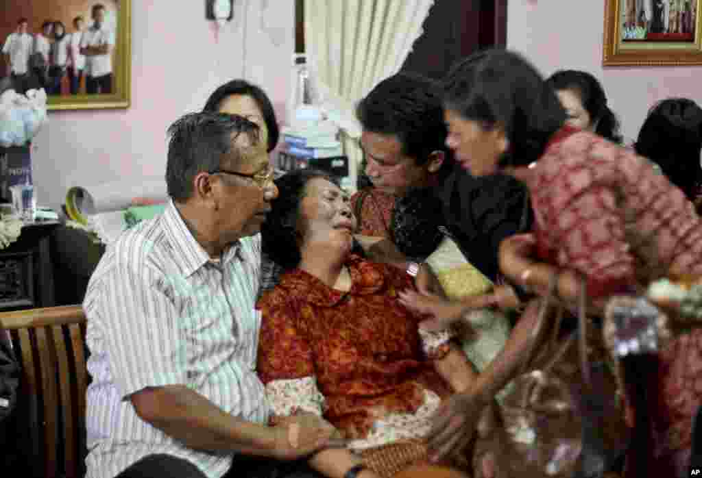 Anggota keluarga menghibur Chrisman Siregar, kiri, dan istrinya Herlina Panjaitan, orangtua Firman Siregar, salah satu warganegara Indonesia yang tercatat di daftar pesawat Malaysia Airlines dengan nomor penerbangan MH370 yang hilang, Medan, Sumatra Utara, Indonesia, 9 Maret 2014. 