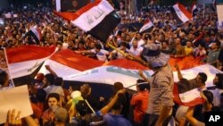 Demonstrators chant in support of Iraqi Prime Minister Haidar al Abadi as they wave national flags during a demonstration at Tahrir Square in Baghdad, Iraq, August 9, 2015.
