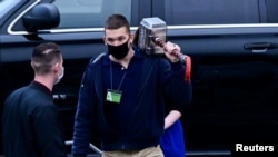 FILE - An employee of the National Archives and Records Administration carries a large hammer engraved with the letters "Trump" at the White House in Washington, Jan. 15, 2021.