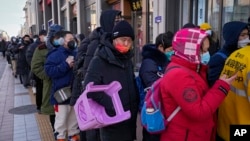 A man carries a plastic chair as he and hundreds of residents line up to visit a store selling 2022 Winter Olympics memorabilia in Beijing, Feb. 7, 2022. 