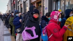 A man carries a plastic chair as he and hundreds of residents line up to visit a store selling 2022 Winter Olympics memorabilia in Beijing, Feb. 7, 2022. 