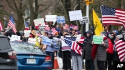 Protesters rallying against COVID-19 restrictions wave to passing cars at Pat Sole Park near the Peace Bridge on Saturday, Feb. 12, 2022, in Buffalo, N.Y. (AP Photo/Joshua Bessex)
