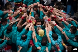 Participants join hands to build the base of a human tower at the "diada Castellera'' during the Saint Eulàlia celebrations in Barcelona, Spain, Feb. 11, 2022.
