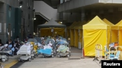 Pasien mengenakan masker, berbaring di tempat tidur di area luar rumah sakit, di tengah pandemi COVID-19 di Hong Kong, 15 Februari 2022. (REUTERS/Lam Yik)