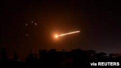 Seberkas cahaya terlihat di langit malam di sekitar ibu kota Suriah, Damaskus, saat Israel melancarkan serangan udara, 24 Februari 2020. (SANA/Handout via REUTERS)/ilustrasi