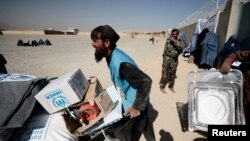 FILE - An UNHCR worker moved aid supplies at a distribution center on the outskirts of Kabul, Oct. 28, 2021. UNHCR said two journalists working for the relief agency and their local colleagues were detained by the Taliban, Feb. 11, 2022.