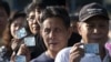 Thai voters show their ID cards as they queue to cast their ballot at a polling station in Bangkok on Feb. 2, 2014.