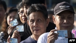 Thai voters show their ID cards as they queue to cast their ballot at a polling station in Bangkok on Feb. 2, 2014.