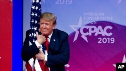 FILE - President Donald Trump hugs the American flag as he arrives to speak at Conservative Political Action Conference, CPAC 2019, in Oxon Hill, Md., March 2, 2019. 