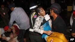 An injured Cambodian is carried by police officers and another visitor after a stampede in Phnom Penh, Cambodia, Monday, Nov. 22, 2010. Thousands of Cambodians celebrating a water festival by the river in the Cambodian capital stampeded Monday night, 