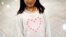 FILE - Janet Mejia, 7, wears a sweater bearing a heart as she waits for two siblings to arrive from El Salvador in Linthicum, Md., Nov. 12, 2015. They were among the first teens to receive permission to travel legally to the U.S. via the Central American Minors program.