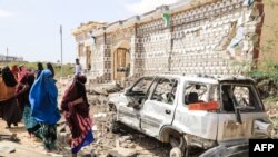 Bebeperapa perempuan Somalia melewati puing-puing mobil dan bangunan yang rusak pasca serangan militan al-Shabab di Mogadishu, Rabu pagi (15/2). 