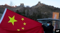 A visitor holds the Chinese flag near the Badaling section of the Great Wall of China on the outskirts of Beijing on Feb. 8, 2022.