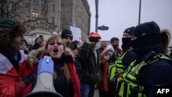 A woman faces off with police during a protest over pandemic health rules outside the parliament of Canada in Ottawa on Feb. 11, 2022. 