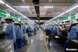 中国广东东莞的工人为一家美国公司的RiotPWR移动游戏控制器在生产线上工作。（2021年12月7日）