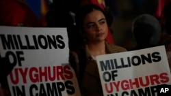 A protester holds a placard as she takes part in a small demonstration against the holding of the 2022 Winter Olympic Games in China, at Piccadilly Circus in London, Feb. 3, 2022.