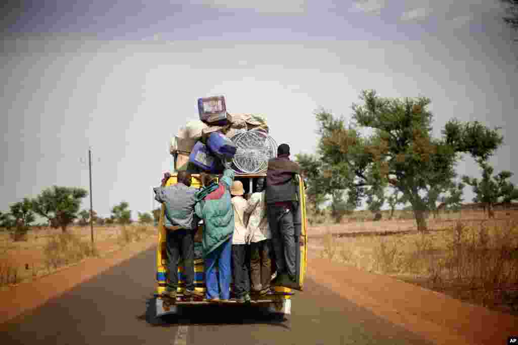 Malians hang on the back of a packed minibus as they drive to Marakala, central Mali, 240 kilometers from Bamako, January 22, 2013.