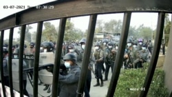 Riot police holding shields and guns march towards a gate of the Mandalay Technological University in Mandalay, Myanmar, March 7, 2021, in this still image obtained by Reuters from a CCTV footage.