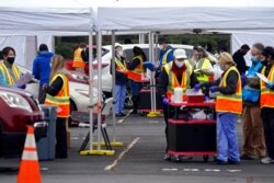 FILE - Wake County Health Department workers along with nurses and volunteers from area hospitals and emergency services are seen during a drive-through COVID-19 mass vaccination event at PNC arena in Raleigh, N.C., Feb. 11, 2021.