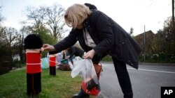 A member of the 'Hurst Hookers' knitting group attaches a knitted figure of a Grenadier Guard to a post in a pre-coronation 'yarn bombing' in the village of Hurst, near Reading, England, April 21, 2023.