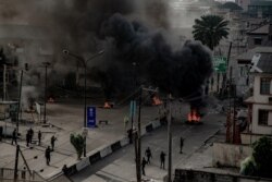 Armed men are seen near burning tires on a street in Lagos, Nigeria Oct. 21, 2020, in this image obtained from social media. (Credit: UnEarthical)