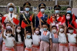 FILE - Students take a picture with the People's Liberation Army during morning assembly at a secondary school, on the 100th founding anniversary of the Communist Party of China, in Hong Kong, July 1, 2021.