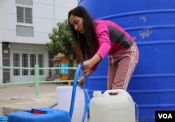 អ្នក​ស្រី​ វ៉ាន់ វលក្ខណ៍ អ្នក​លក់​ដូរ​ក្នុង​បុរី​មួយនៅសង្កាត់​សំរោង​ក្រោម​ ខណ្ឌ​ពោធិ៍​សែន​ជ័យ រាជ​ធានី​ភ្នំពេញ កំពុង​បង្ហូរ​ទឹក​ពី​បាសាំង​ទឹក ដាក់​ធុង​សម្រាប់​ប្រើប្រាស់ នាថ្ងៃ​ទី​៩ ខែ​កុម្ភៈ ឆ្នាំ​២០២២។ (កាន់ វិច្ឆិកា/វីអូអេ)