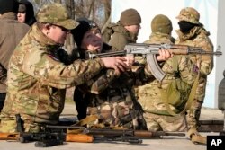 Instruktor pokazuje ženi kako da koristi automatsku pušku "Kalašnjikov", u sklopu treninga ekstremno desne grupe, u Kijevu, 13. februara 2022.