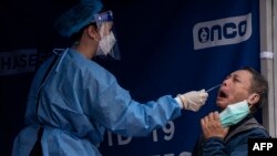 A man (R) is tested at a temporary testing site for COVID-19 in Hong Kong on February 12, 2022, as authorities scrambled to ramp up testing capacity following a record high of new infections. (Photo by Louise Delmotte / AFP)