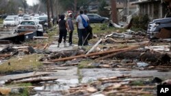 People walk amongst debris from destroyed homes after a tornado tore through the eastern neighborhood in New Orleans, Feb. 7, 2017.