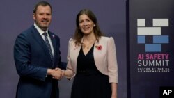 FILE - Menteri Luar Negeri Inggris untuk Sains, Inovasi dan Teknologi Michelle Donelan (kanan), berjabat tangan dengan Menteri Industri dan Sains Australia Ed Husic, setibanya di AI Saftey Summit di Bletchley Park, Milton Keynes, Inggris, Rabu, 1 November 2023. 