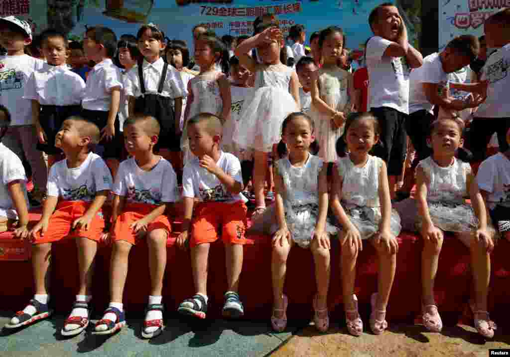 在中国广州长隆野生动物园，三胞胎儿童庆祝世界上唯一的大熊猫三胞胎萌萌、帅帅和酷酷的4岁生日（2018年7月29日）。