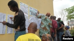 Des électeurs cherchent leur nom sur la liste électorale affichée sur un mur, dans un bureau de vote à Lagos, au Nigeria, le 25 février 2023.