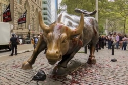 In this freeze frame made from a video, fake blood covers the iconic Charging Bull statue near Wall Street in New York, Oct. 7, 2019.