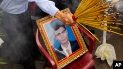 រូបឯកសារ៖ សហជីពម្នាក់កាន់ធូបនៅពីលើរូបថតរបស់លោក ជា វិជ្ជា ដែលជាអតីតប្រធានសហជីពសេរីកម្មករ ក្នុងអំឡុងពិធីគម្រប់ខួប ៦ ឆ្នាំនៃការសម្លាប់លោក ជា វិជ្ជា នៅរាជធានីភ្នំពេញ ថ្ងៃទី ២២ ខែមករា ឆ្នាំ ២០១០។ 